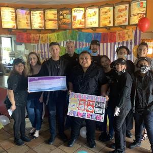 Andrew German with his work crew, holding an oversized check