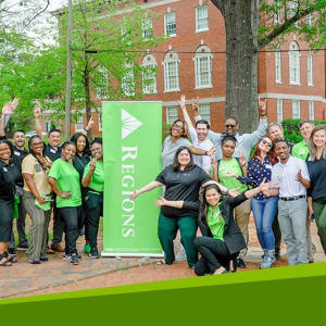 A group of people posing outside next to a Regions banner