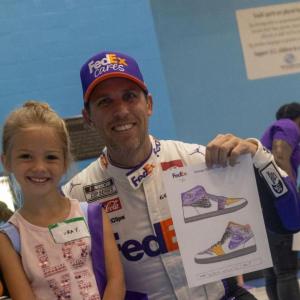 Denny Hamlin holding up a child's show drawing.
