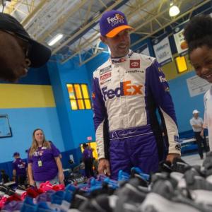 Denny Hamlin and a child looking at rows of shoes.