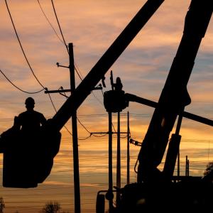silhouette of someone working on a powerline