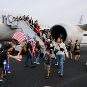 Passengers disembark from an American Airlines plane, a line of people there to greet them on the tarmac.