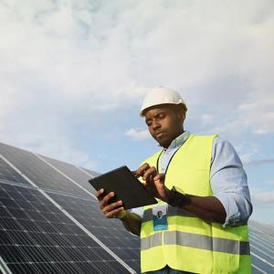 A person using a tablet next to solar panels.