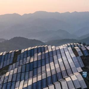 Aerial view of a hilly landscape covered in solar panels.