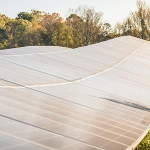 a person in safety gear walking alongside solar panels