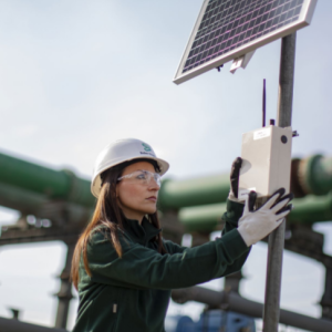 a worker in a hard hat and gloves works on a solar panel 