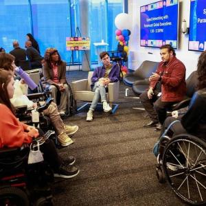 A person speaking with a group of others in a circle around them. "Speed Networking" signs behind them. 