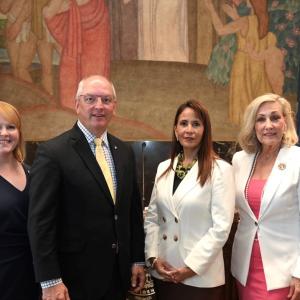 Four people in a government building, posed for the camera.