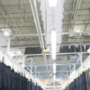 A large warehouse with racks of identical hanging clothing.