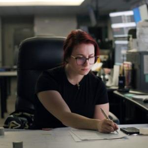 An employee writing on a piece of paper in an office setting.