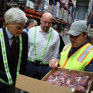 The Senator looks into a box of wrapped meat