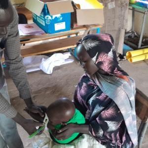 A woman in Sudan holds her baby as he is screened for malnutrition with a mid-upper arm circumference (MUAC) band. /Photo by Pedro Javaloyes