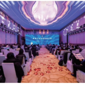 People seated in a room with digital display projected on the ceiling and front.