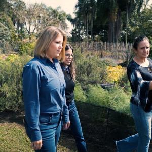 Three people walking through a garden