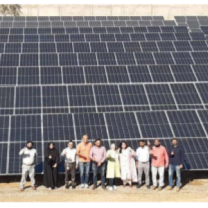 People posed in front of a field of solar panels.