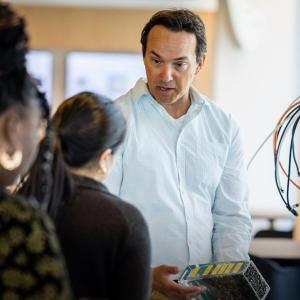 A person talking to others, holding an electronic device