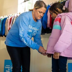 person helping a child with a new coat