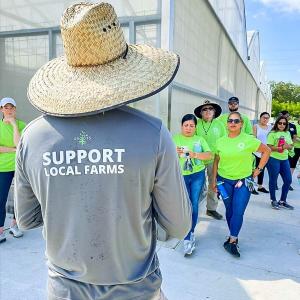 A person wearing a long sleeved t-shirt that reads "support local farms"