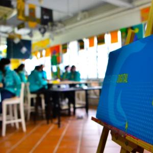 close up of a "Surf Smart 2.0" poster. A group of people seated at tables is blurry in the background