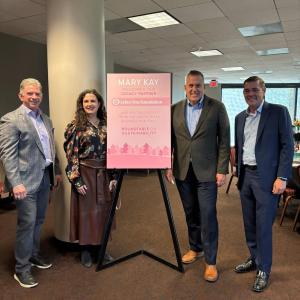 Four people standing by a sign "Mary Kay welcomes our legacy partner Arbor Day Foundation."
