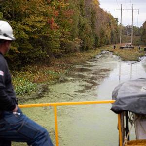 Duke employee on a boat in the swamp