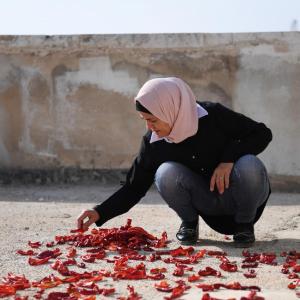 Lama*, 45, prepares tomato paste outside in Aleppo.