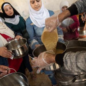 In Aleppo, women living in a shelter—rehabilitated by Action Against Hunger—queue for their daily meals.
