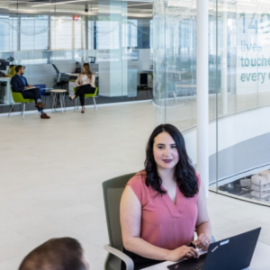 People seated in an open space, working on laptops.
