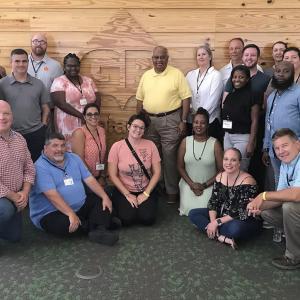 a large group of people in front of a "GP" logo in wood siding