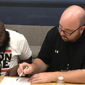 two people looking at a piece of paper, one pointing with a pen