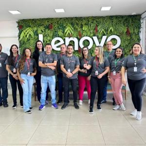 Group photo of employees against a wall with the lenovo logo on