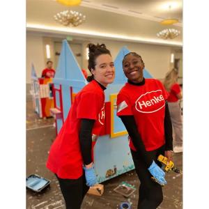 Two people smiling, wearing matching henkel t-shirts.