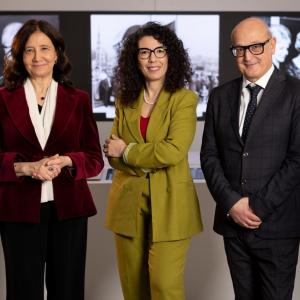 Three people standing in front of black and white photos.