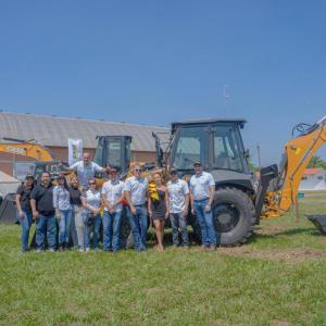 A team of people posed in front of two digging-type construction vehicles