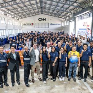 A large team posed in an open covered building, most with one fist half-raised. 
