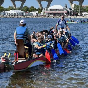 A group in a long boat paddling on a body of water.