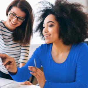 Two people pointing to the same screen in an office setting.