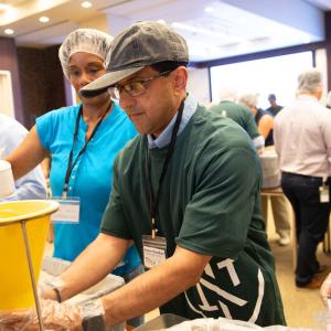 Volunteers in assembly lines packing food.