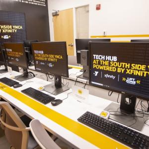 two rows of desktop computers, chairs in a room "Tech Hub" on all the monitors