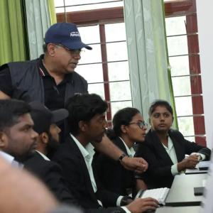 An adult looking over students using computers.