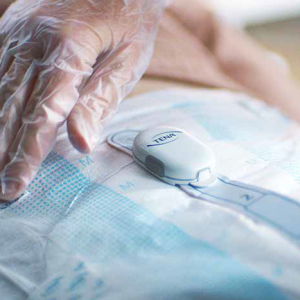a gloved hand touching an incontinence underwear with an attached monitor