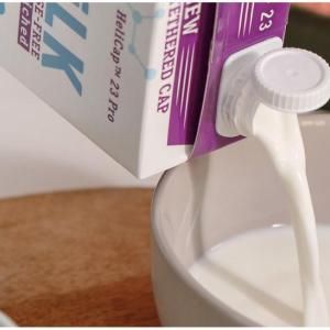A container of milk being poured into a bowl.