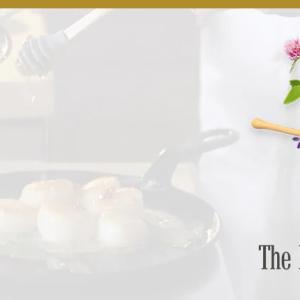 A faded background of a pan on a stove "The buzz on Honey" and honey pot and flowers.