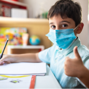 Young student wearing mask giving thumbs up
