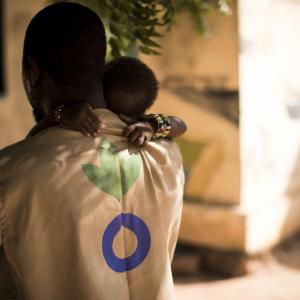 An Action Against Hunger Aid Worker holds a child in his arms in Mali. // Photo by Toby Madden