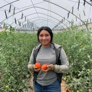 Gloribel holding two tomatoes
