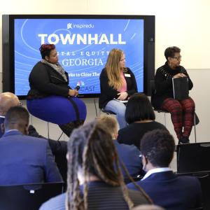 Five people seated on stage with digital display of "Townhwll digital equity Georgia" behind them. A small audience in front.