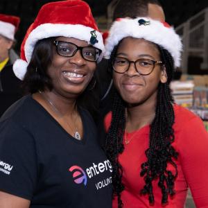 Two volunteers in santa hats posed together.