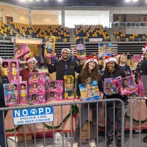 Volunteers holding up toys in a gymnasium.