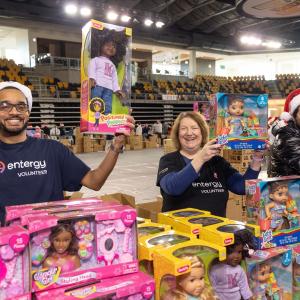 Volunteers holding up toys from a table full.